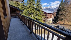 A balcony with a view of snow-covered mountains and a wooden building.