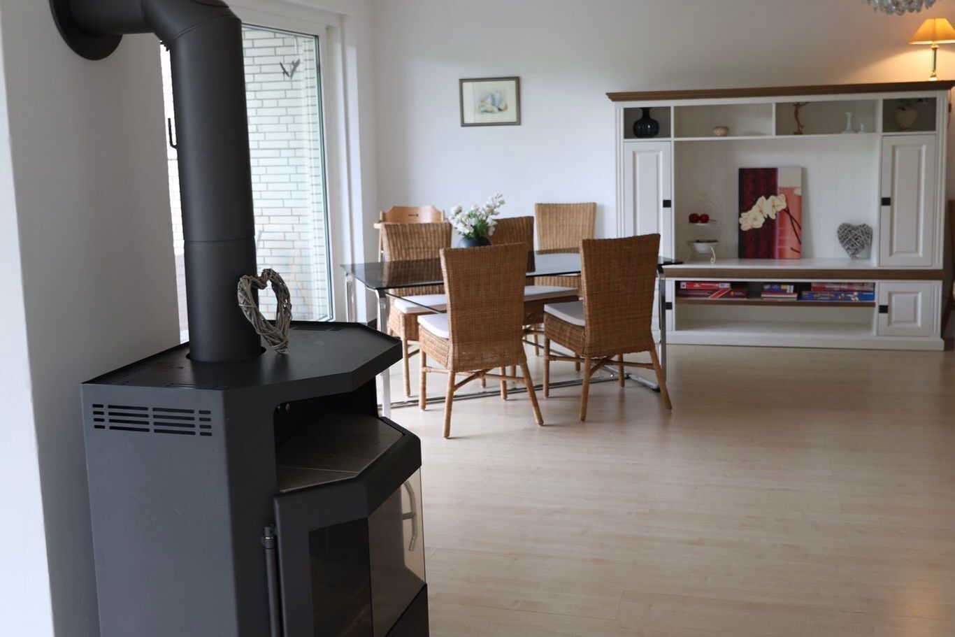 Una cocina moderna con estufa negra, sillas de mimbre y una mesa de comedor.