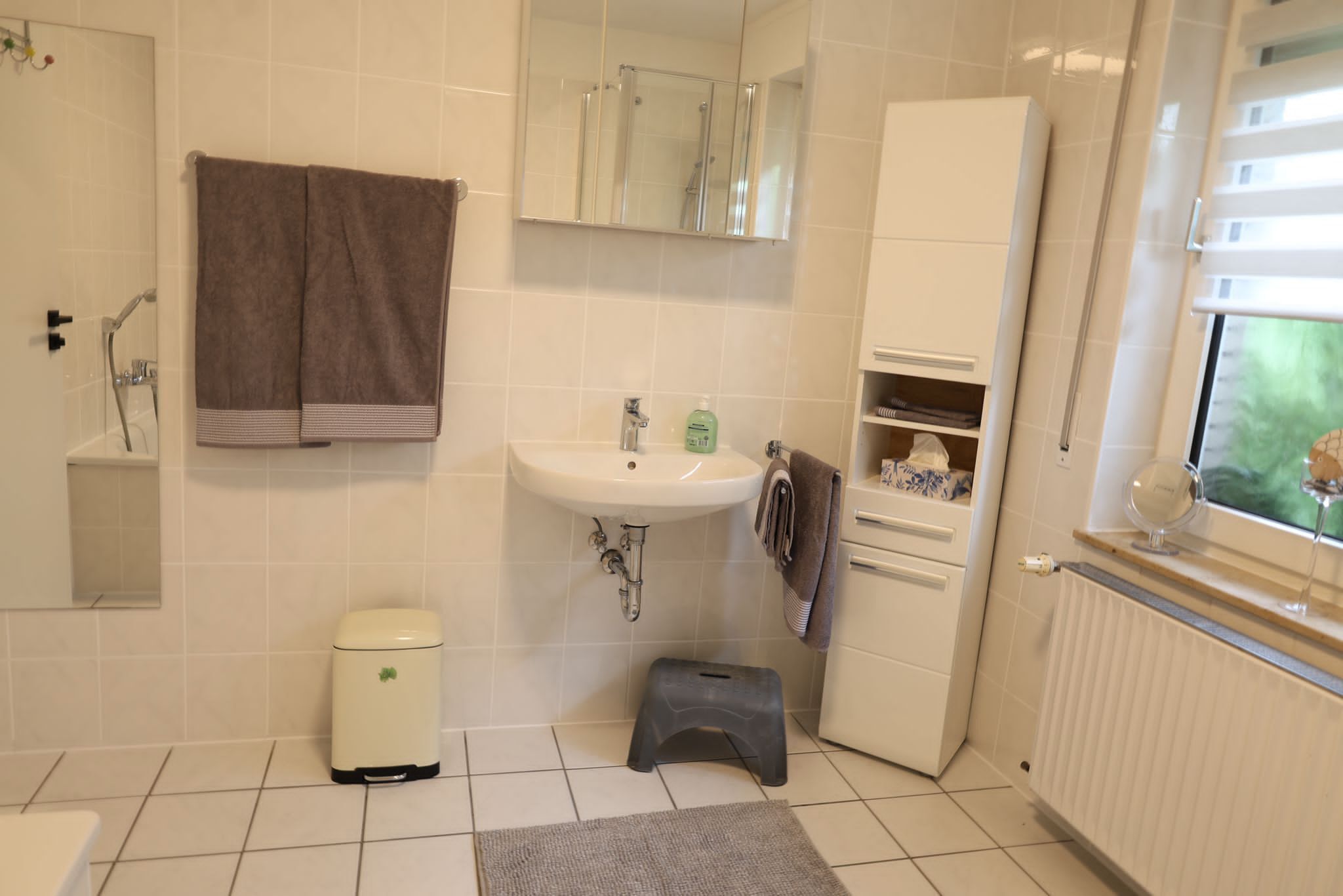 Un baño con lavamanos blanco, espejo, toallero, inodoro y radiador.