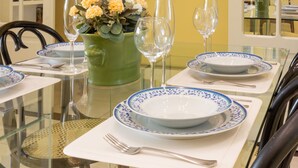 Ein Esstisch, gedeckt mit Tellern, Gläsern und einer Blumenvase.