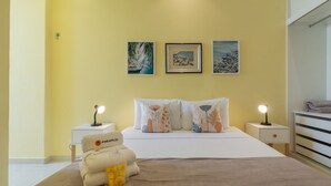 Ein Schlafzimmer mit einem Bett, zwei Nachttischen und drei an der Wand befestigten Kunstwerken.