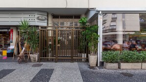 Ein Schaufenster mit Metallgitter, Blumentöpfen und einem gefliesten Gehweg.