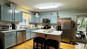 A modern kitchen with grey cabinets, stainless steel appliances, and a wooden floor.