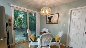 A dining area with wicker chairs, a glass table, and a pendant light.