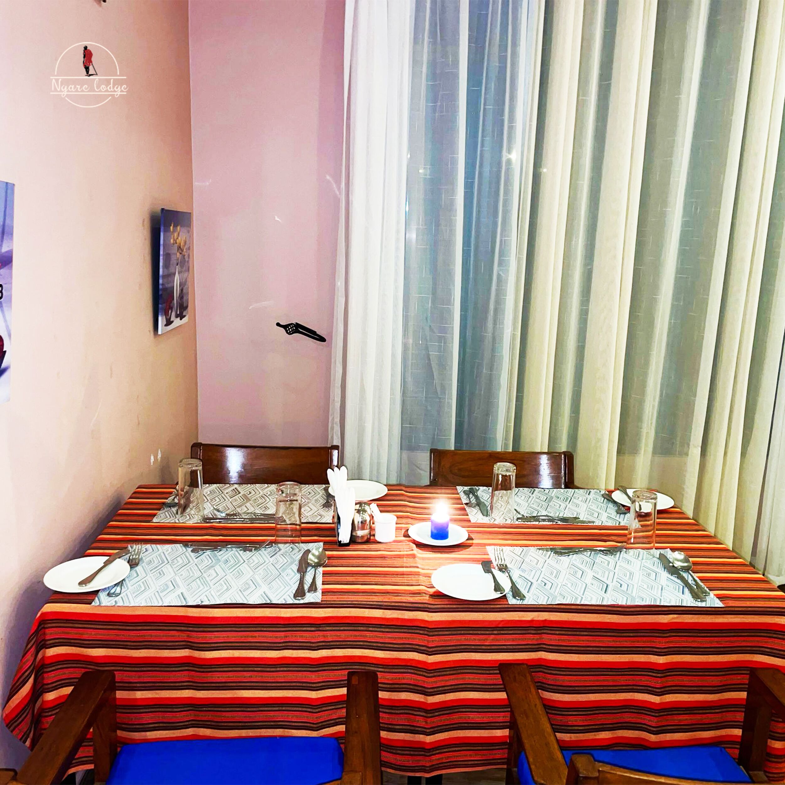A dining area with a table set for two, featuring striped tablecloths and wooden chairs.