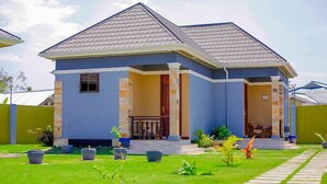 Une maison à deux étages, avec un toit en tuiles, un porche à l’avant et une pelouse bien entretenue.