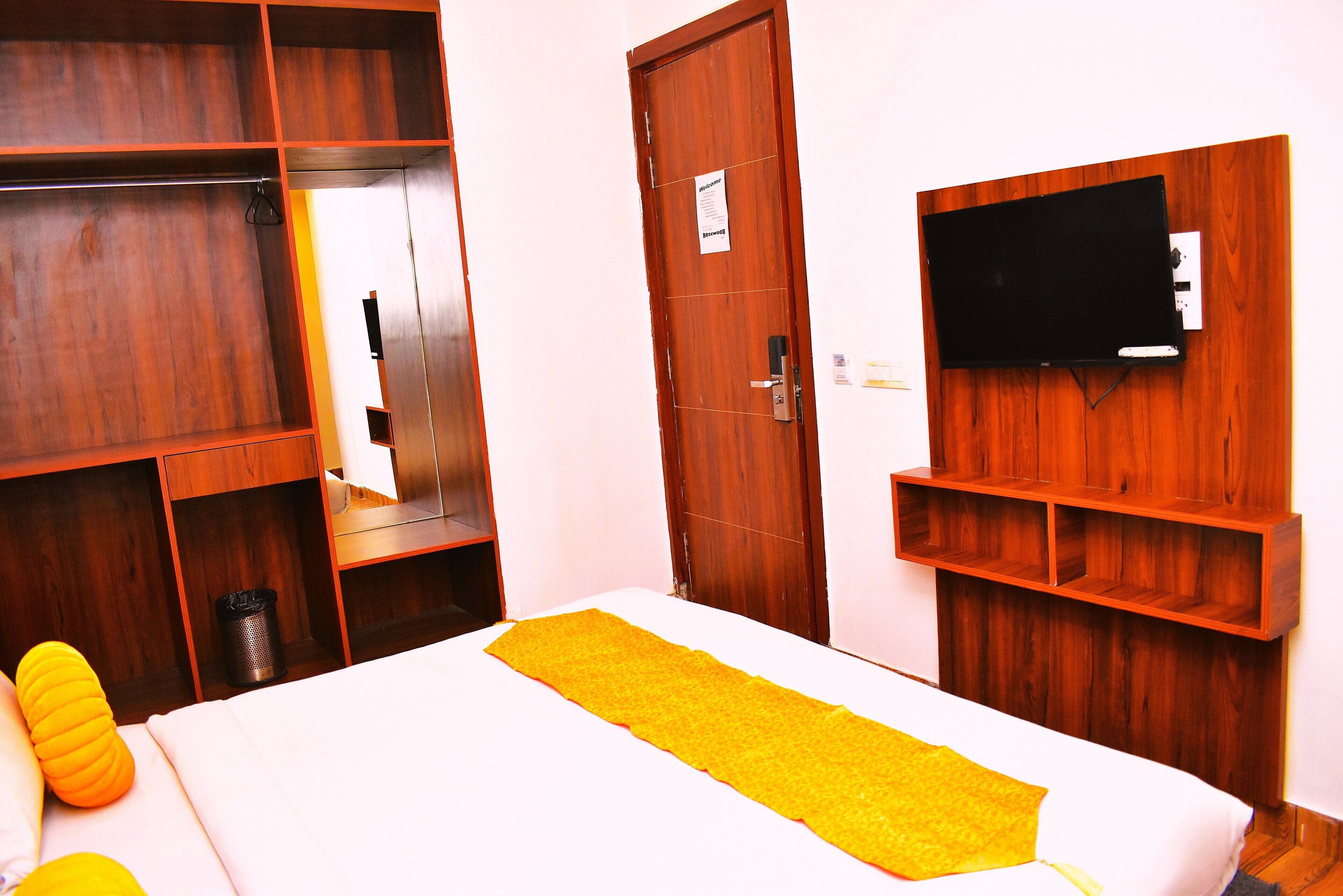Ein Hotelzimmer mit Bett, Holzschrank und Wandfernseher.
