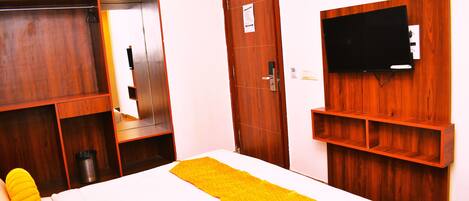 Ein Hotelzimmer mit Bett, Holzschrank und Wandfernseher.