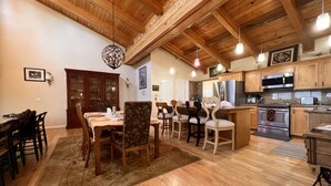 A spacious kitchen with wooden cabinets, a central island, stainless steel appliances, and a dining area with a wooden table and chairs. - Lx121 Pristine Tahoe Experience (Zephyr Cove)