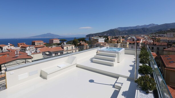 A rooftop terrace with a pool, overlooking a coastal town and mountains. - The Square in Sorrento (Sorrento)