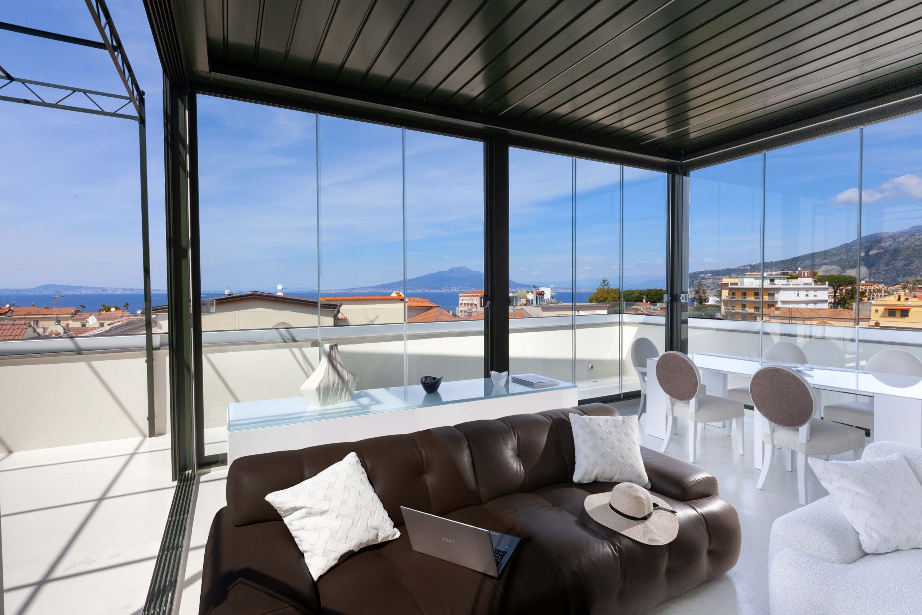 Un balcón moderno con sofá de cuero, una mesa de comedor y sillas.