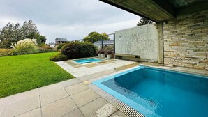 Una piscina con un muro de piedra y un césped.