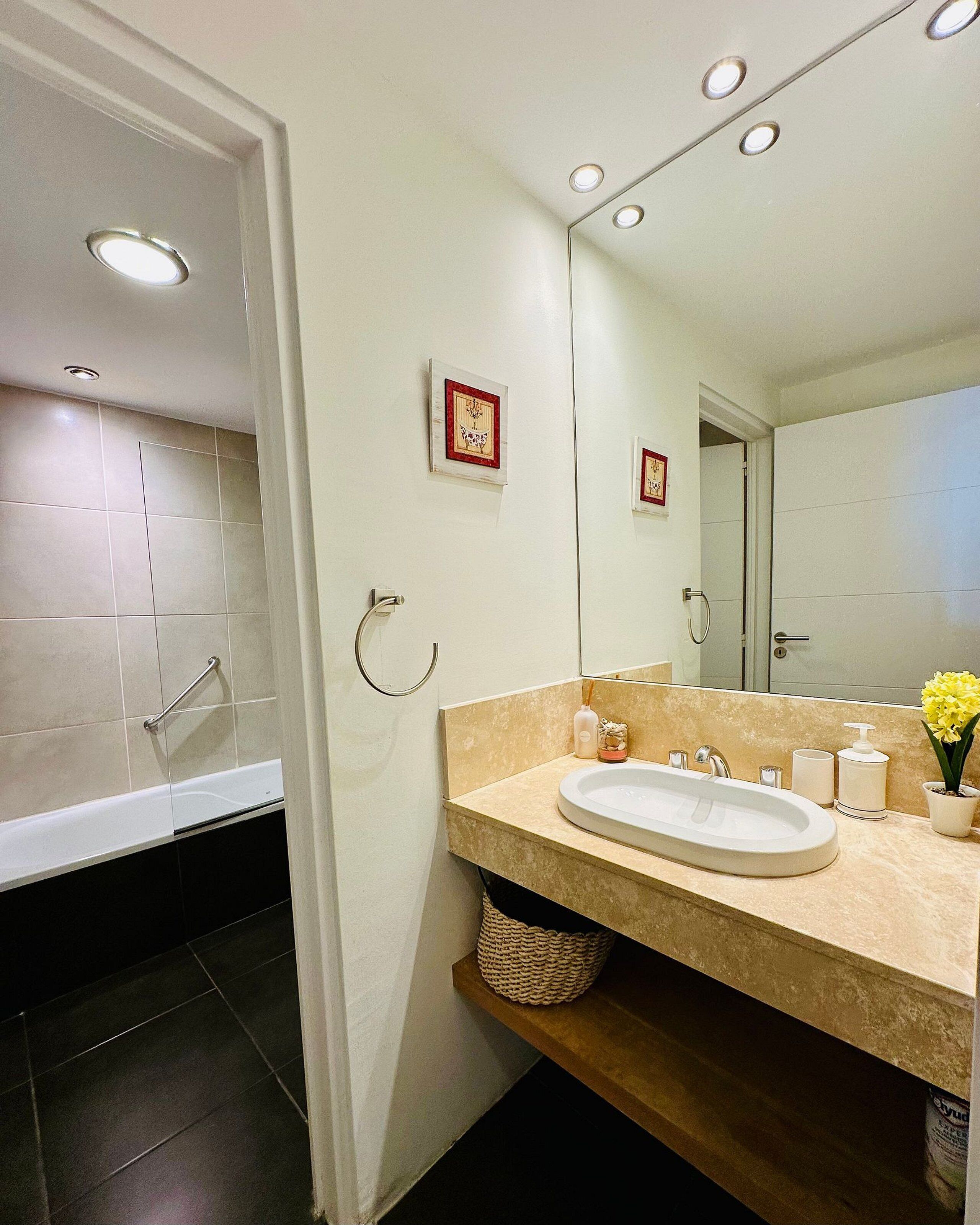 Een moderne badkamer met een badkuip, een wastafel met spiegel en een handdoekrek.