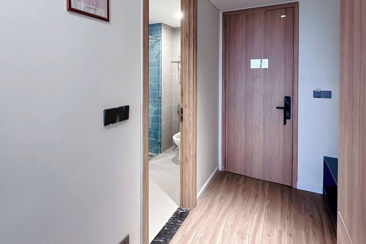 Un couloir doté d’un plancher en bois, d’une porte en bois et d’un tableau encadré représentant un flamant rose, accroché au mur.