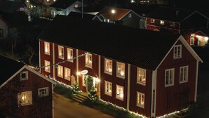 Una casa de madera roja con varias ventanas y un pequeño árbol de Navidad decorado con luces.