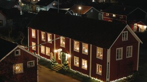 Una casa de madera roja con varias ventanas y un pequeño árbol de Navidad decorado con luces.
