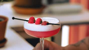 Un cóctel con fresas y un palillo, sostenido por una persona.
