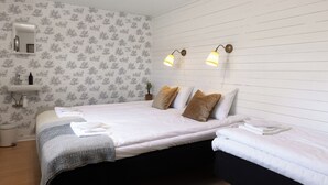 Un dormitorio con una cama grande, dos mesitas de noche, un espejo y una lámpara fijada a la pared.
