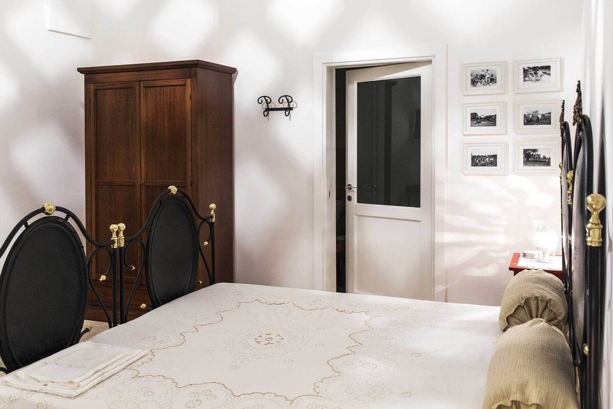 A bedroom with a bed, a wardrobe, a door, and wall-mounted pictures.
