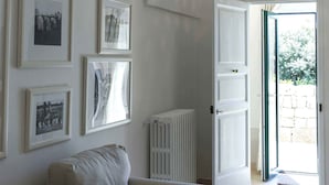 A spacious room with a high arched ceiling, a white radiator, and a door leading to an outdoor area. - Trapetum-Salento Domus by Oikia Vacanze (Cursi)