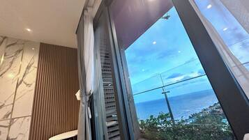 Ein modernes Badezimmer mit einem großen Fenster und Meerblick.