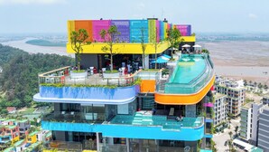 Un hotel de varios pisos con piscina en la azotea y zonas de estar al aire libre.