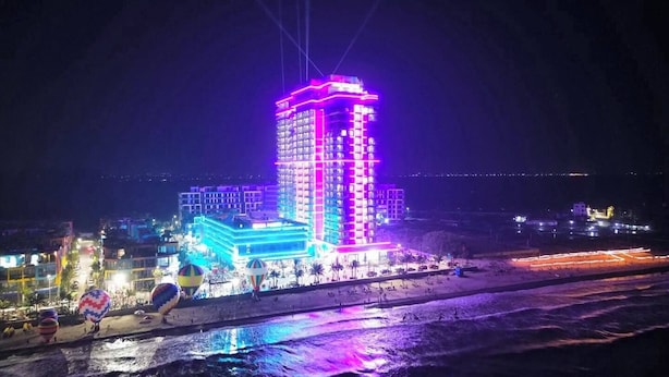Un hotel muy iluminado con diseño moderno, con varios pisos y una entrada destacada.