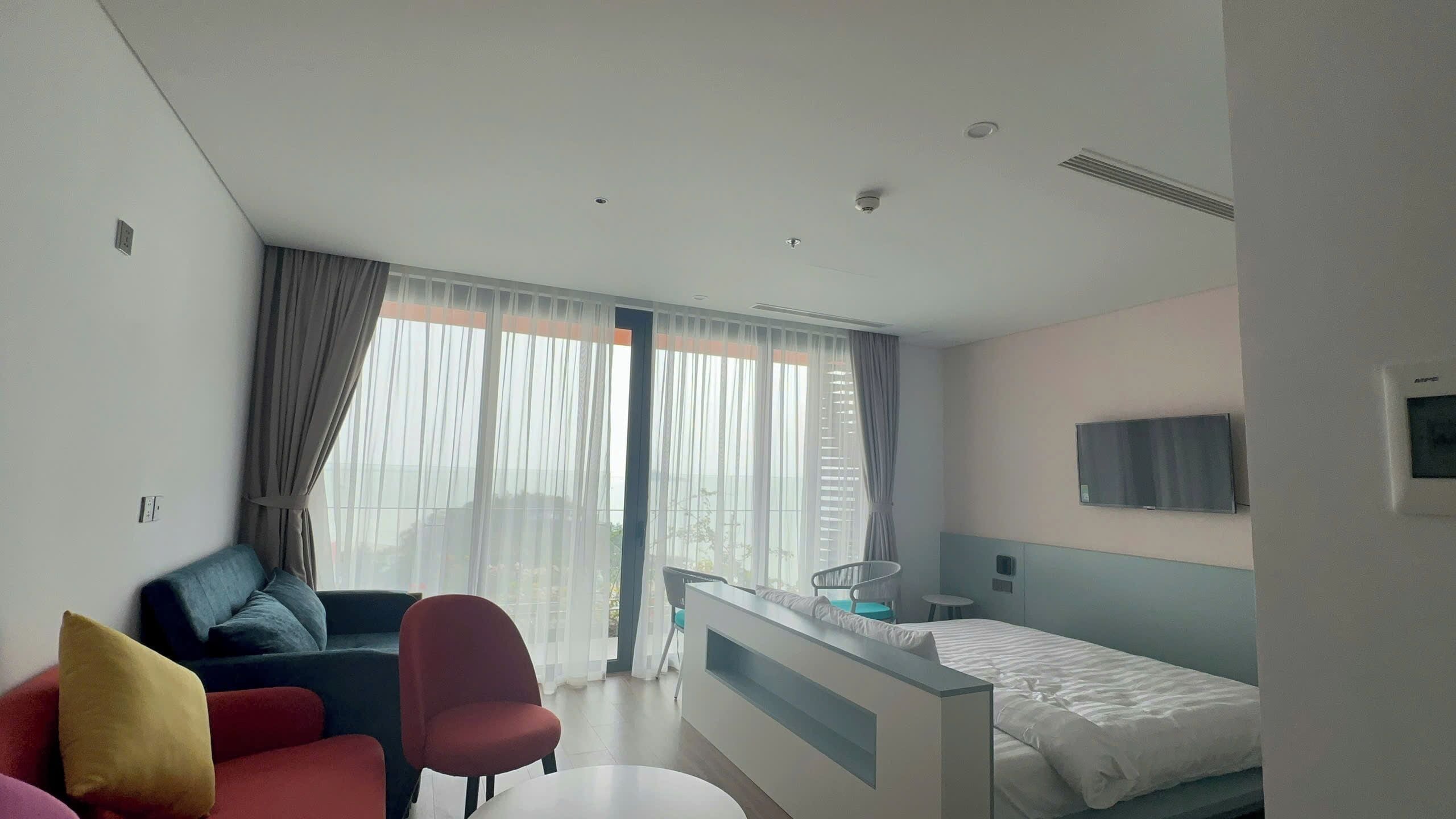 A hotel room with a bed, a desk, a chair, a couch, and a TV.