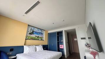 Ein Hotelzimmer mit einem Bett, einem Schreibtisch, einem Stuhl, einem Gemälde, einem Kleiderschrank und einem Spiegel.