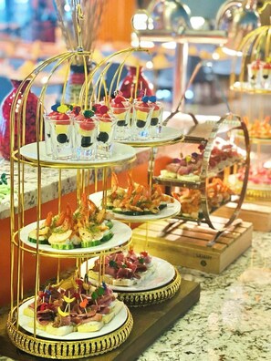 Un présentoir à plusieurs niveaux où sont disposés divers desserts et amuse-gueules sucrés.