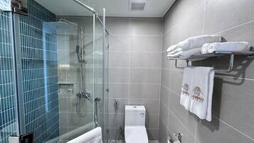 A modern bathroom with a glass-enclosed shower, a toilet, and a towel rack with neatly folded towels.