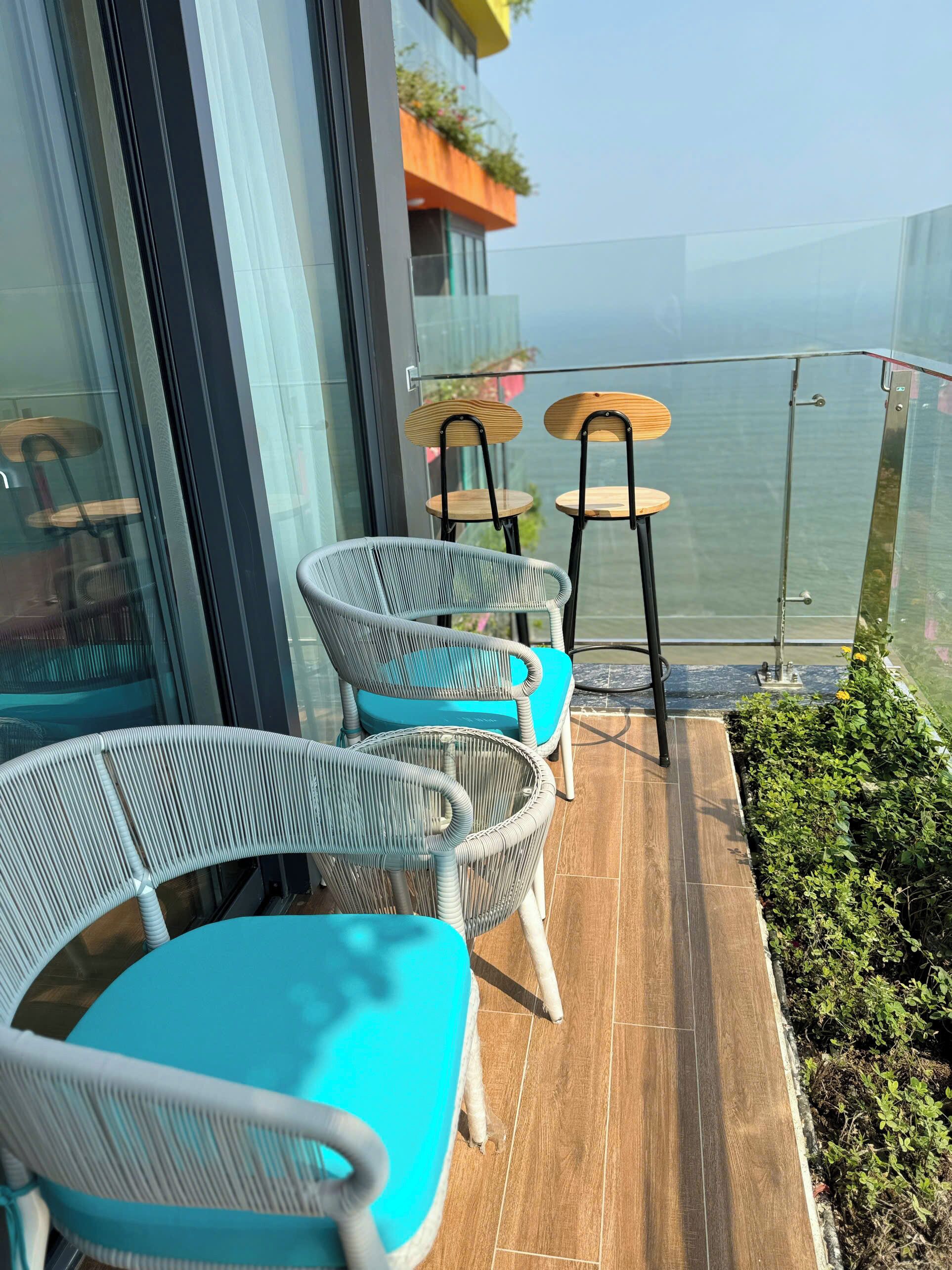 A balcony with wicker chairs and a small table, overlooking a body of water.