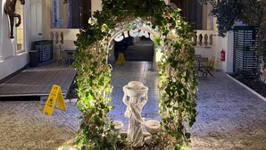 An indoor courtyard with a decorative archway, a statue, and a tiled floor. - Oasis Inn Budapest (Budapest)