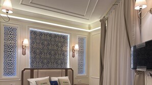 A hotel room with a bed, bedside tables, a desk, a chair, a TV, and a patterned rug. - Oasis Inn Budapest (Budapest)