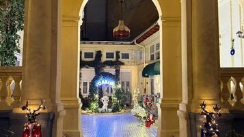 Entrada de un hotel con un arco decorado con luces navideñas y un cartel que dice 'Oasis Inn'.