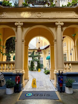 A hotel entrance with an arched doorway, a wet floor sign, and a doormat with the hotel logo. - Oasis Inn Budapest (Budapest)
