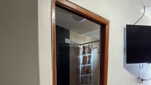 A bathroom with a toilet, a shower curtain, and a mounted television. - Hoteles Perú Hosting (Piura)