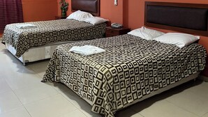 A hotel room with two beds, a nightstand, a wall-mounted air conditioner, and a window with curtains. - Hoteles Perú Hosting (Piura)