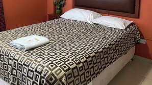 A hotel room with a bed, a nightstand, an air conditioning unit, and a potted plant. - Hoteles Perú Hosting (Piura)