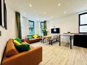 A modern living room with a sofa, a dining table, and a TV. - Premium 3-Bed Apt - Heart of Town - Walk to Beach (Bournemouth, Christchurch and Poole)
