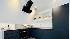 A modern kitchen with dark cabinetry, a built-in oven, and a countertop with a kettle and toaster.