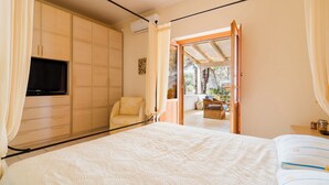 Ein Schlafzimmer mit Bett, Fernseher, Kleiderschrank und Blick ins Freie.