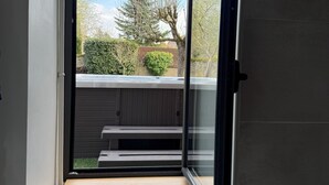 Habitació amb finestra que dona a un jardí, un banc integrat i un radiador.