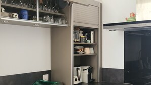 Cuina amb forn encastrat, cafetera i escorredora de plats verda.