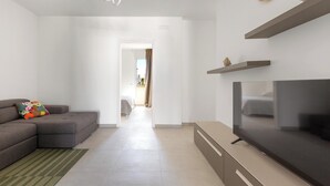 Una sala de estar moderna con un sofá seccional gris, un televisor de pantalla plana y una decoración minimalista.