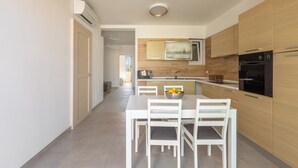 Una cocina moderna con armarios de madera, una mesa de comedor con sillas y un cuenco de fruta.