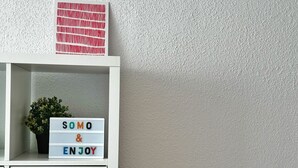 A white shelf with a small plant and a sign that says "SOMO & ENJOY". - Tierruca Green 30023 (Somo)