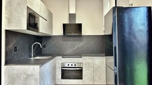 Una cocina moderna con horno empotrado, refrigerador de acero inoxidable y microondas.