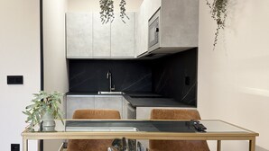 Cozinha moderna com ilha central, forno embutido e plantas penduradas.