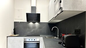 Una cucina compatta con forno a incasso, microonde e tostapane.